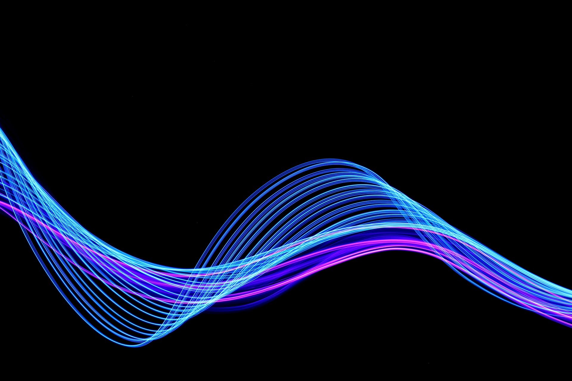 Light painting photography - long exposure, blue and purple fairy lights in swirling patterns on a clean black background