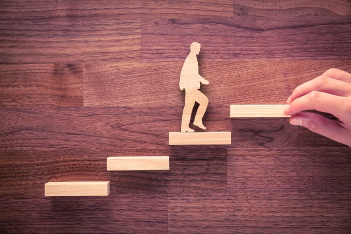 A person climbing steps, depicted with wooden blocks