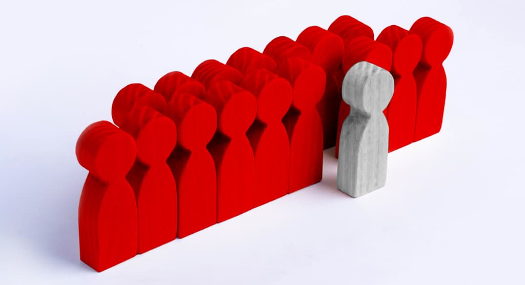 wooden people in red with one standing out not in red