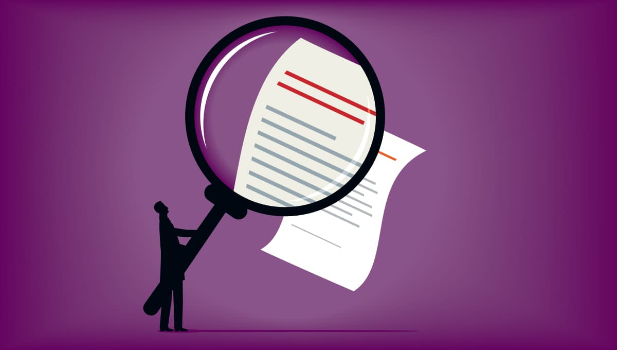 Man examines contract with magnifying glass