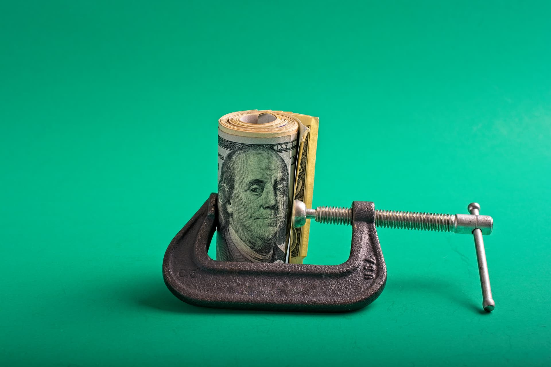 Clamp squeezing a roll of US dollar notes