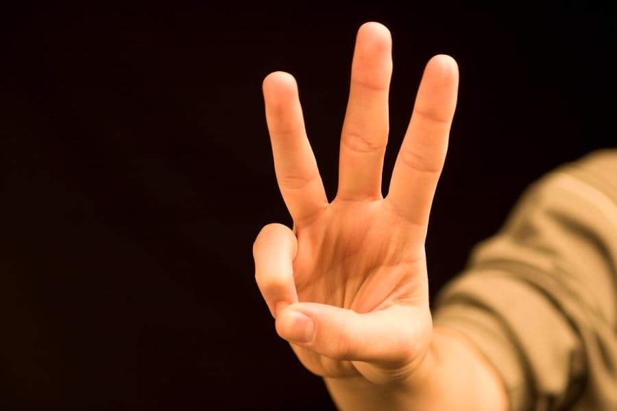Photo of a hand holding up three fingers.