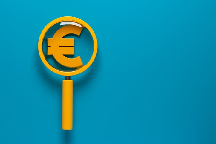 A euro symbol being placed under a magnifying glass