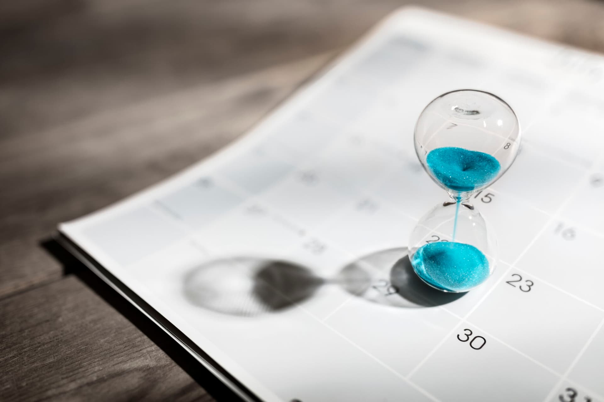 A calendar with a blue hourglass placed on top