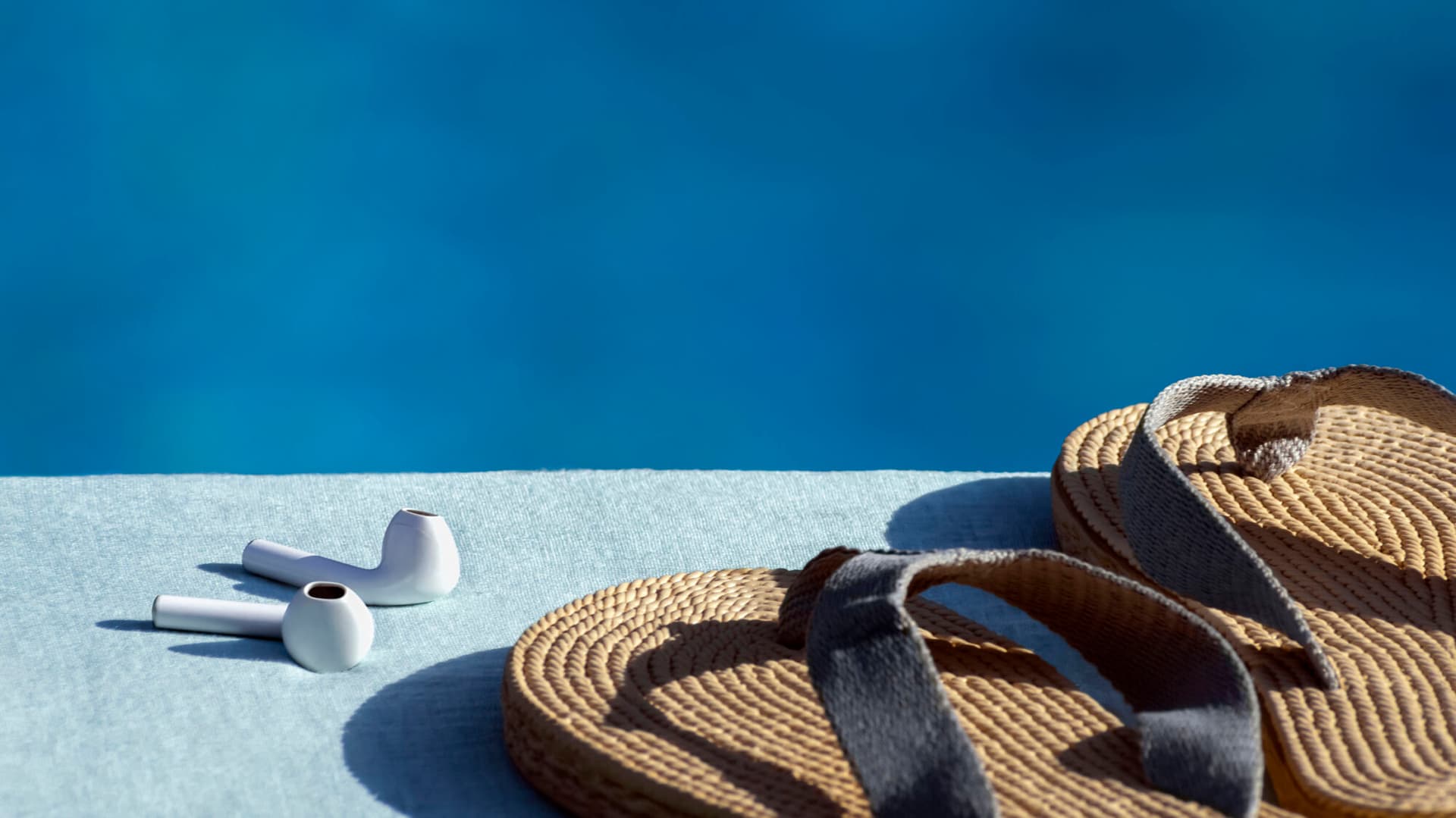 Headphones and sandals by the side of a pool