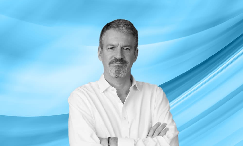 Headshot of Paul Buckley, chief executive and managing partner at FIRSTAvenue, against a blue background