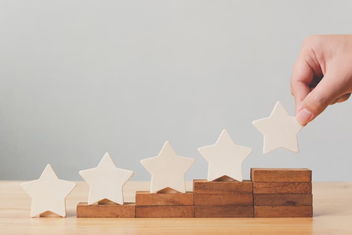 Hand putting wooden five star shape on table. The best excellent business services rating customer experience concept.