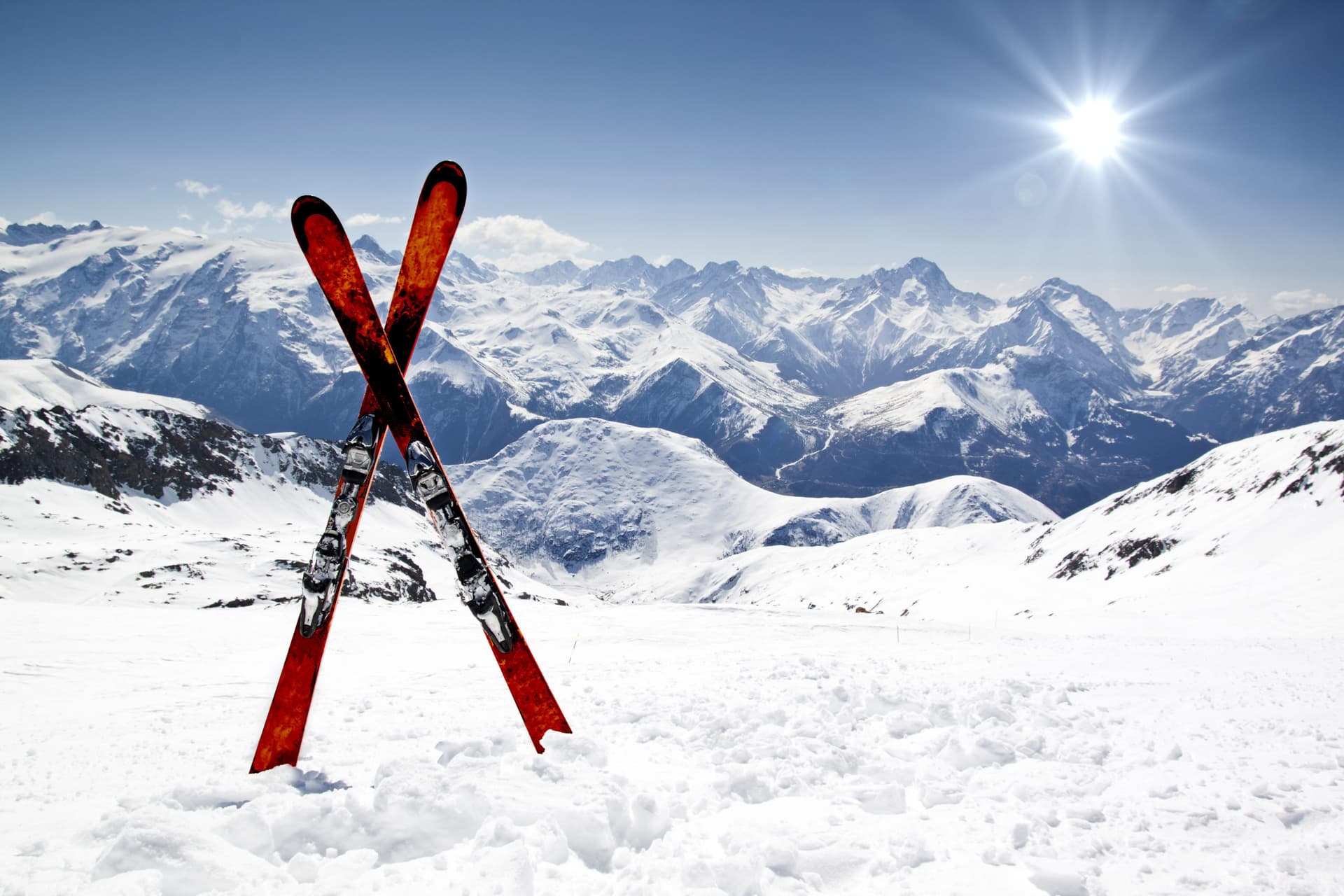 Pair of red skis crossed and wedged in snow on mountain