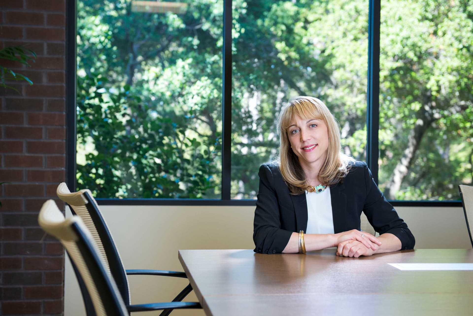 Andrea Auerback sitting at a desk, trees in background